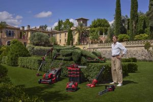 A famous racing driver stood in front of an artificial boxwood topiary racing car